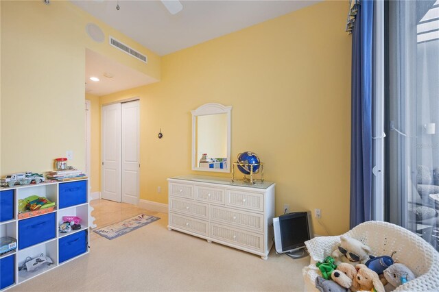 bedroom with ceiling fan, light carpet, and a closet