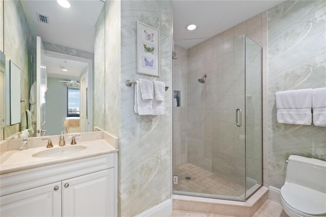 bathroom featuring tile patterned floors, toilet, vanity, and a shower with shower door