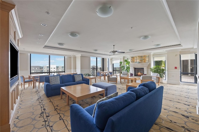 living room with a wealth of natural light, a raised ceiling, and ceiling fan