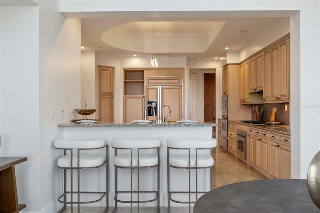 50 Central Ave Unit 17Phb, Sarasota, FL 34236 - kitchen with built in appliances, a breakfast bar, a peninsula, decorative backsplash, and light stone countertops