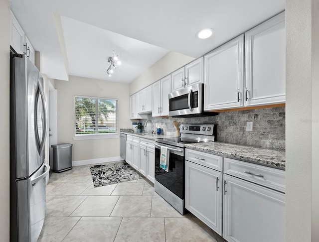 kitchen featuring stainless steel appliances, white cabinetry, backsplash, and light stone counters