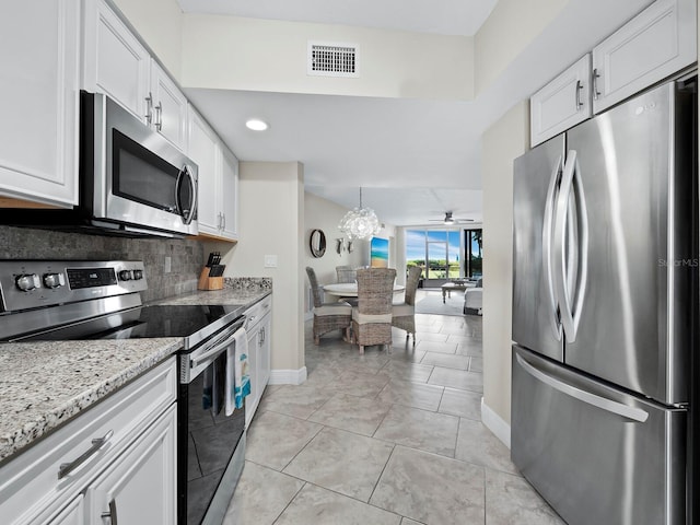 kitchen with stainless steel appliances, ceiling fan, light stone counters, white cabinetry, and backsplash