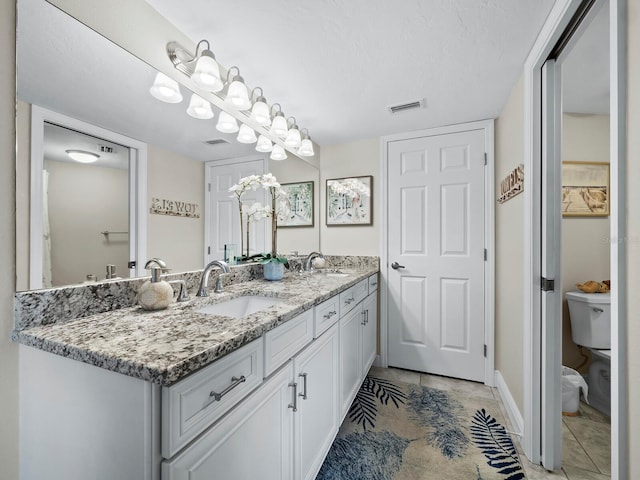 bathroom with toilet, tile patterned flooring, and vanity