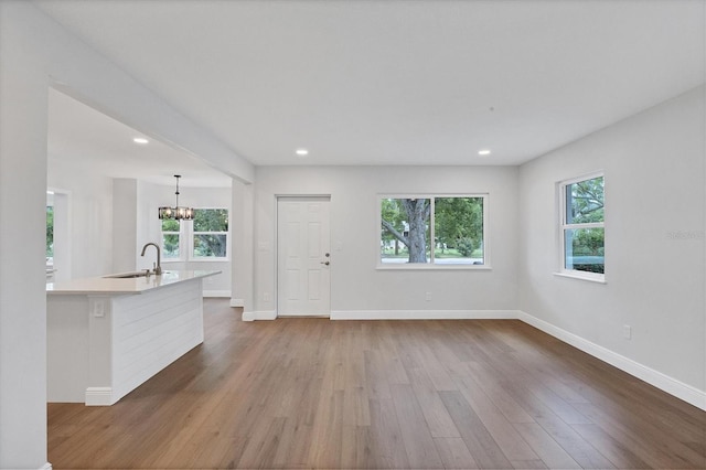 unfurnished living room with hardwood / wood-style floors, sink, and a chandelier