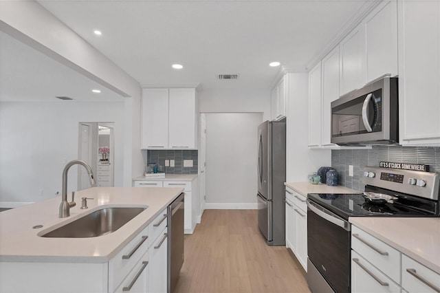 kitchen featuring backsplash, sink, light hardwood / wood-style flooring, a kitchen island with sink, and stainless steel appliances