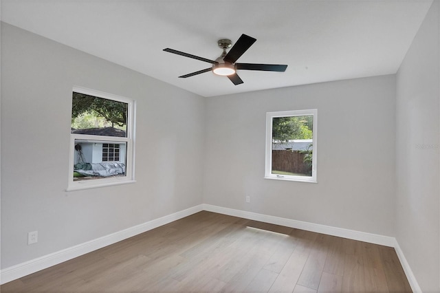 spare room featuring ceiling fan, wood-type flooring, and plenty of natural light