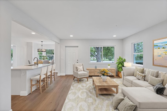 living room featuring sink, light hardwood / wood-style flooring, and a chandelier