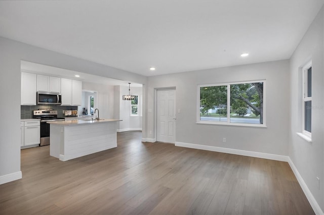 kitchen with stainless steel appliances, white cabinets, light wood-type flooring, and plenty of natural light