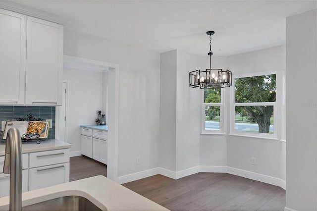 kitchen featuring backsplash, decorative light fixtures, white cabinetry, a chandelier, and dark wood-type flooring