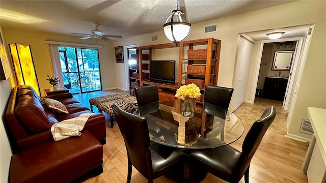 dining area with sink, a textured ceiling, light hardwood / wood-style floors, and ceiling fan