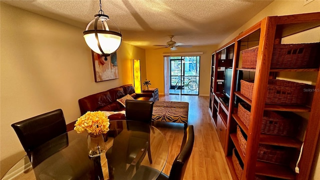 dining space featuring ceiling fan, hardwood / wood-style flooring, and a textured ceiling