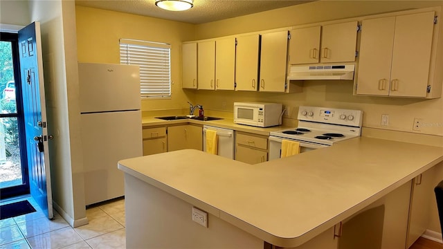 kitchen featuring under cabinet range hood, light countertops, a sink, white appliances, and a peninsula