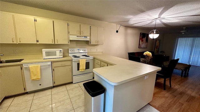 kitchen featuring a peninsula, under cabinet range hood, white appliances, and light countertops