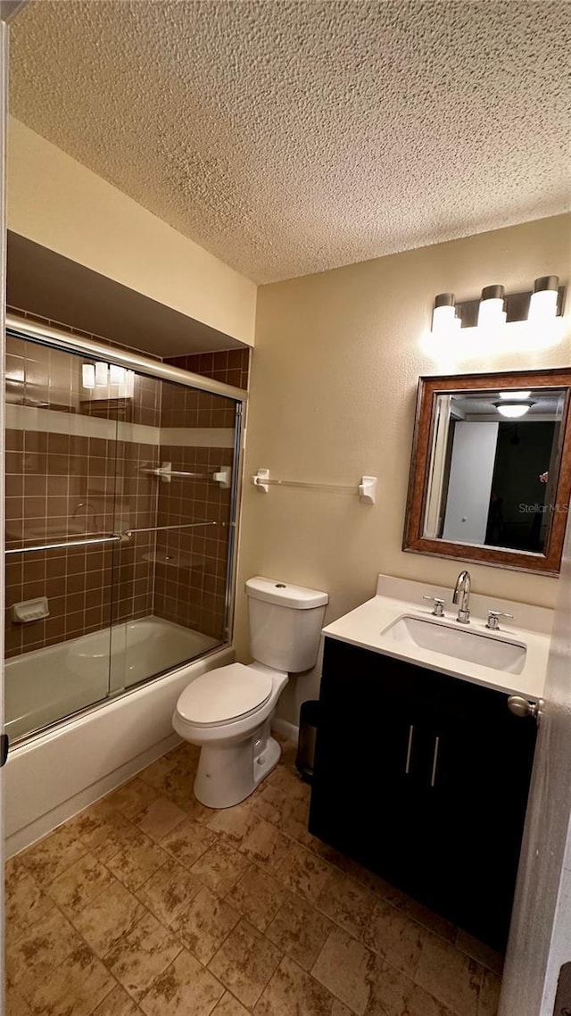 full bathroom with a textured ceiling, toilet, bath / shower combo with glass door, and vanity