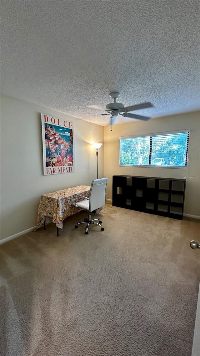 carpeted office space featuring ceiling fan and a textured ceiling