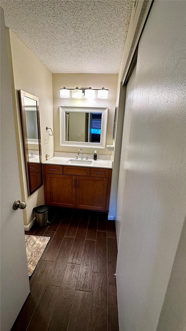 bathroom with wood finished floors, a textured ceiling, and vanity