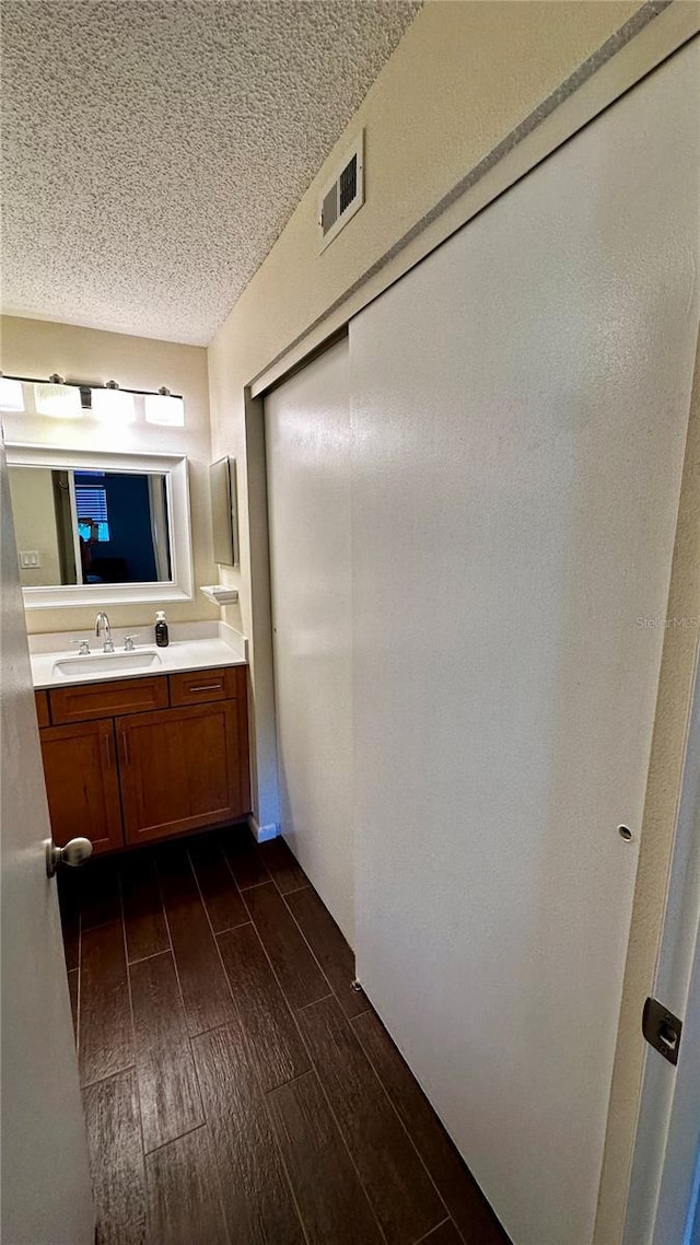 bathroom with vanity, wood finished floors, visible vents, and a textured ceiling