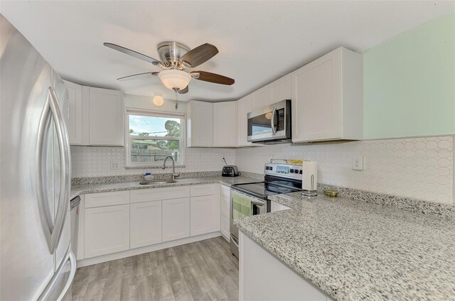 kitchen featuring white cabinetry, sink, stainless steel appliances, light stone counters, and light hardwood / wood-style floors