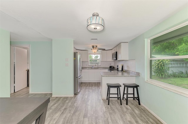 2900 Siesta Dr, Venice, FL 34293 - kitchen featuring stainless steel appliances, backsplash, white cabinets, a sink, and a peninsula