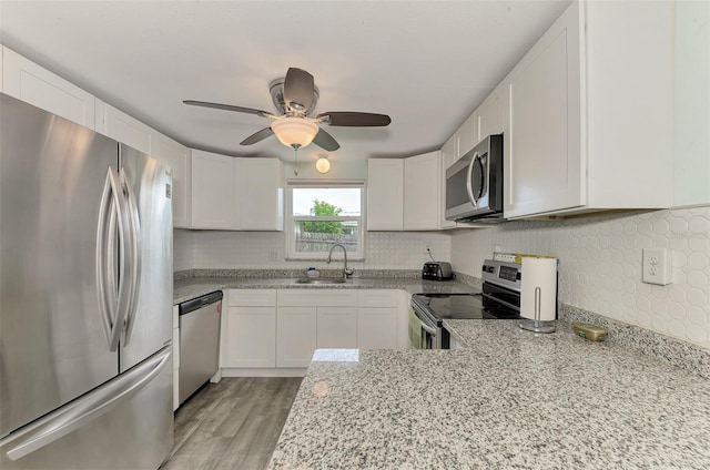 2900 Siesta Dr, Venice, FL 34293 - kitchen with appliances with stainless steel finishes, a sink, light stone counters, and white cabinets