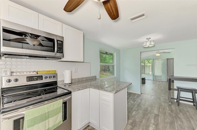 2900 Siesta Dr, Venice, FL 34293 - kitchen featuring visible vents, backsplash, appliances with stainless steel finishes, white cabinetry, and a peninsula