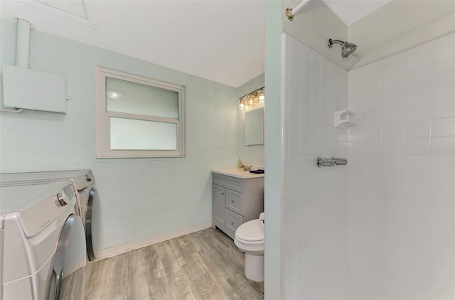 2900 Siesta Dr, Venice, FL 34293 - bathroom featuring toilet, wood finished floors, vanity, tiled shower, and washing machine and clothes dryer