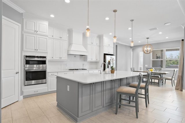 kitchen with light countertops, custom range hood, backsplash, appliances with stainless steel finishes, and white cabinetry