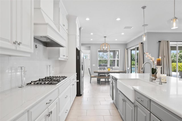 kitchen featuring gray cabinetry, premium range hood, a sink, appliances with stainless steel finishes, and backsplash