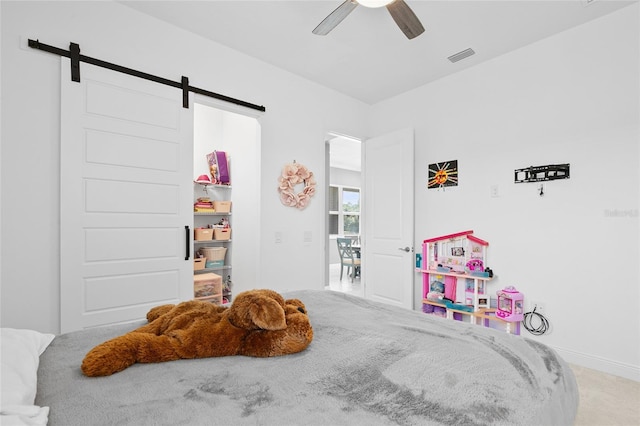 carpeted bedroom with a barn door, visible vents, and ceiling fan