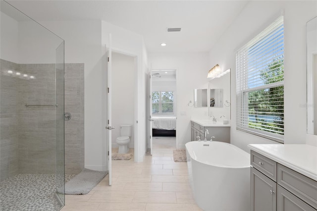 full bath with visible vents, toilet, a tile shower, vanity, and ensuite bath