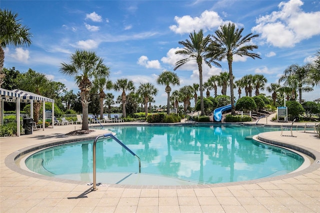 community pool featuring a water slide, a patio area, and a pergola