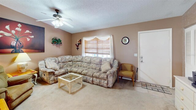 living room with a ceiling fan, vaulted ceiling, a textured ceiling, and light colored carpet