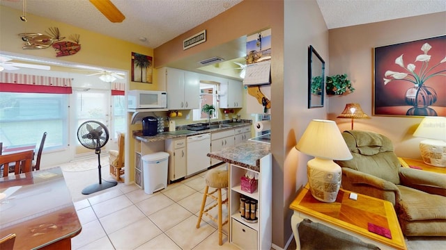 kitchen with light tile patterned floors, white appliances, a textured ceiling, ceiling fan, and white cabinets