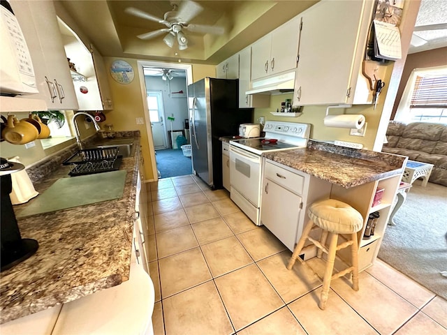 kitchen with white cabinetry, a sink, white appliances, under cabinet range hood, and a kitchen breakfast bar