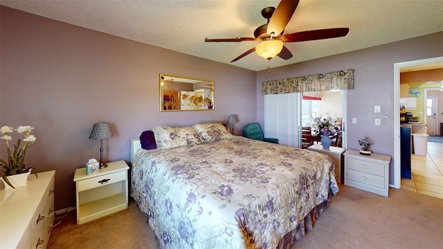 bedroom with light carpet, ceiling fan, and a textured ceiling