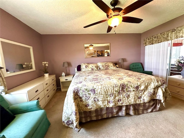 bedroom with ceiling fan, light colored carpet, and a textured ceiling