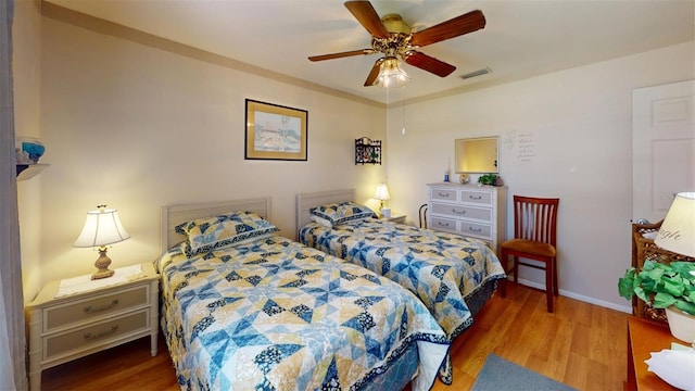 bedroom featuring a ceiling fan, visible vents, baseboards, and wood finished floors