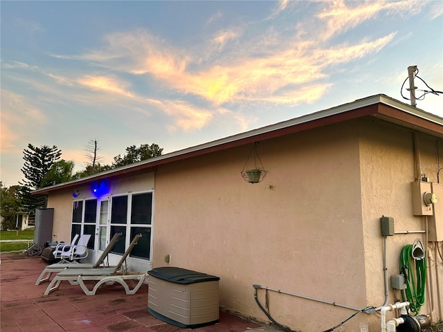 property exterior at dusk featuring a patio and stucco siding