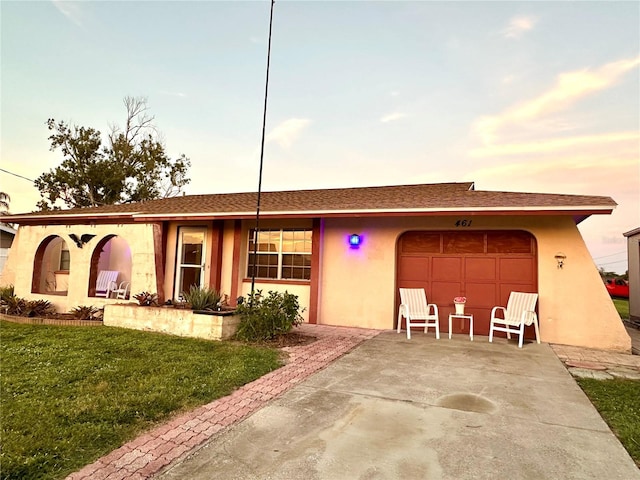 ranch-style home featuring a garage and a lawn