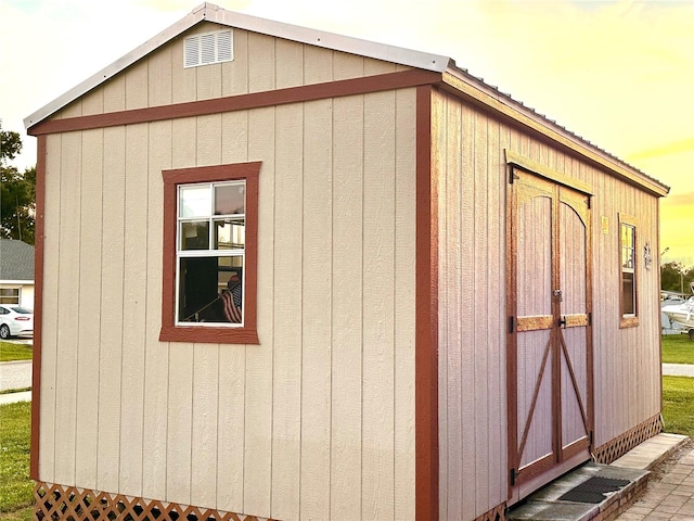 outdoor structure at dusk featuring an outbuilding and a storage shed