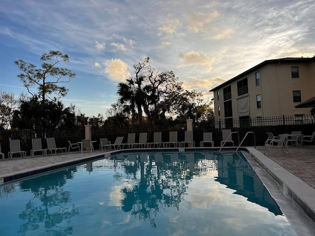 pool at dusk with a patio area