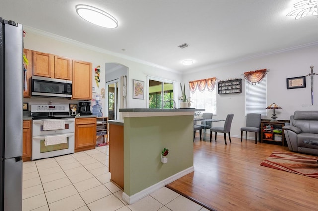 kitchen featuring light wood-type flooring, appliances with stainless steel finishes, a center island, and crown molding