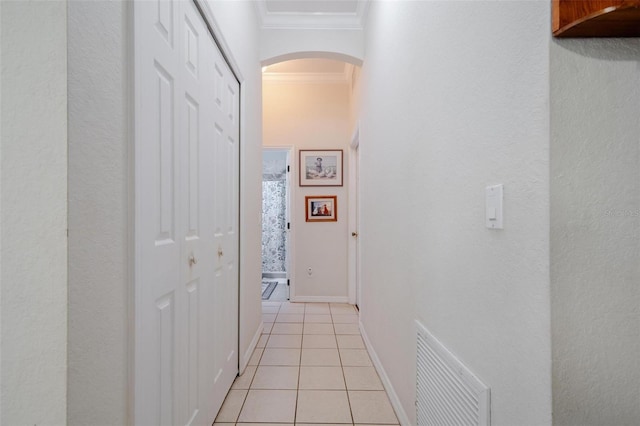 hallway with ornamental molding and light tile patterned floors