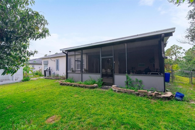 rear view of property featuring a lawn and a sunroom