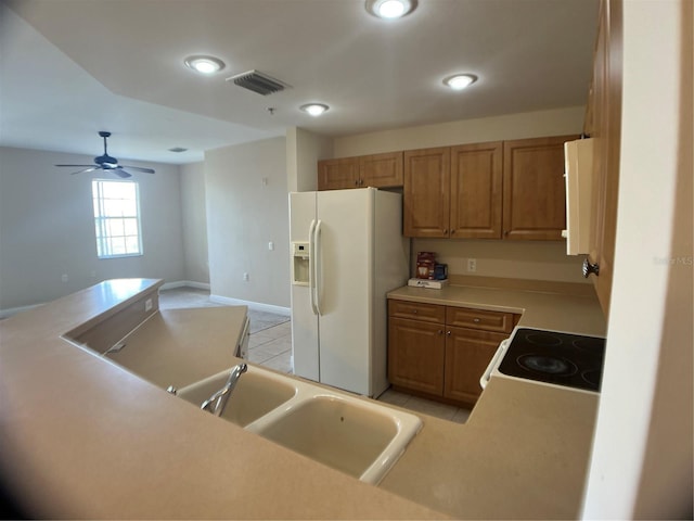 kitchen with ceiling fan, sink, white fridge with ice dispenser, stove, and light tile patterned flooring