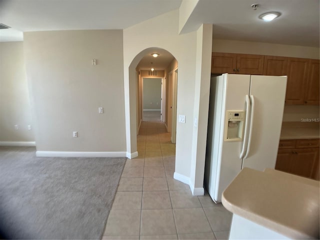 kitchen with light tile patterned floors and white refrigerator with ice dispenser