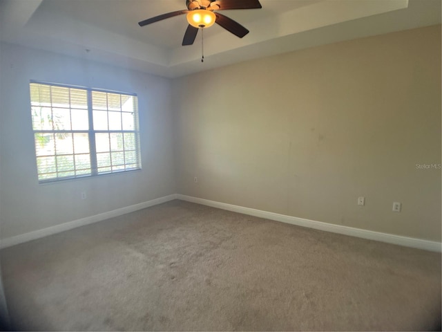 unfurnished room with ceiling fan, a raised ceiling, and carpet floors