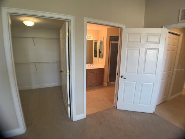 unfurnished bedroom featuring a closet, light carpet, and ensuite bath