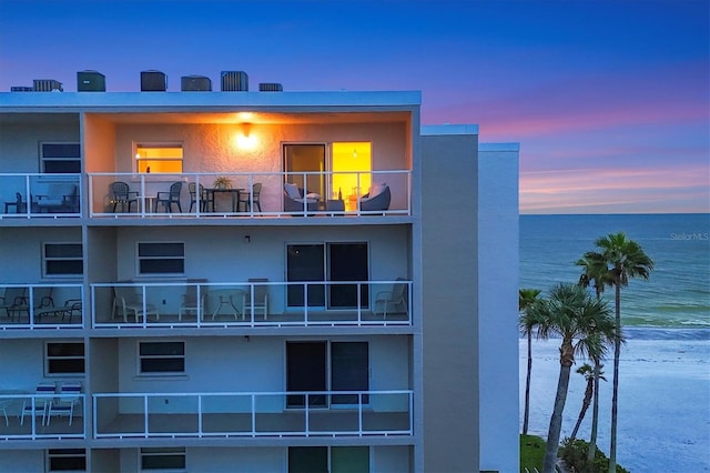 outdoor building at dusk featuring a water view and a view of the beach