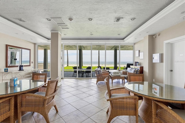 tiled dining space featuring plenty of natural light, a raised ceiling, a water view, and a textured ceiling